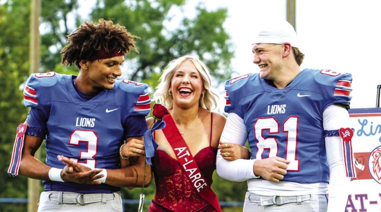 At-Large candidate Lizzy Kliewer grins as her named is called for Homecoming queen in Chandler on Friday night. Her escorts are Darius Wade (left) and Boston Christy (right). Photo/Jennifer Pryor