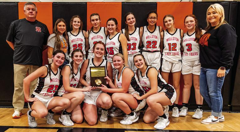 Above, coach Evan Smith and the North Rock Creek Cougars pose with their hardware after winning the Konawa Tournament. The Cougars went in to play Tuesday night against Oklahoma Christian with an 11-0 record and ranked No. 2 in Class 4A. Photo/Sheryl Gowin. Right, the Wellston girls show off the championship trophy from the Davenport tournament. The WLTs beat Meeker, 33-3, in the finals. Coached by Chad Hutchison, the Lady Tigers are 11-3. Photo/Jeremy Self.