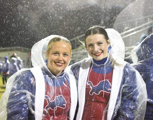 Top, Javarious Wade runs through the rain and past the Dewey defense for a firstquarter touchdown Friday night. Above, cheerleaders Rylee Capps, left, and Jaycee Cross donned plastic ponchos and kept the cheers coming. Photos/Brian Blansett
