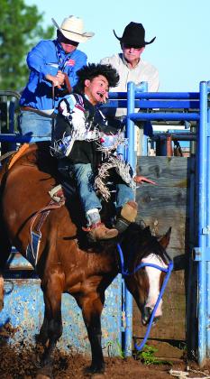 Above, Lexi Helmick of Meeker throws a loop during breakaway roping Sunday night at the International Finals Youth Rodeo in Shawnee. The rodeo continues through Friday night with the championship short go-around. Right, Marley Miller from Chandler heads her horse to the timer line during pole-bending competition in the Monday morning performance Below, bareback bronc rider Blake Huddleston from McLoud comes out of the chute on his bronc Sunday evening. Photos/Brian Blansett