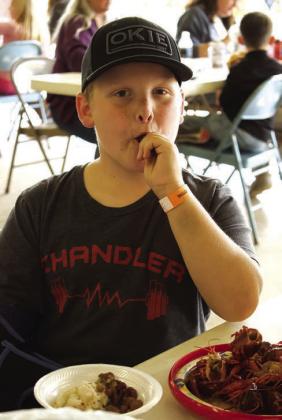 Wyatt Danker enjoys a spicy crawfish at Chandler’s Annual Bell Cow Boil Crawfish Festival on May 1. The festival saw hundreds at the Route 66 Pavilion near Tilghman Park.and featured crawfish from the Oklahoma Crawfish Co. There was live music and games, along with booths set up by local businesses. Photo/Emily Kalka