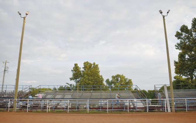 A wide view of the new bleachers and arena lights at the Chandler Round Up Club’s Rodeo Arena next to the high school football field. The club purchased the bleachers from the school in 2022. Right: Jesse and Misty Wright tighten bolts and work to get the bleachers installed at the rodeo arena. Behind them, Clu Harkins works on welding. Photos/Emily Kalka