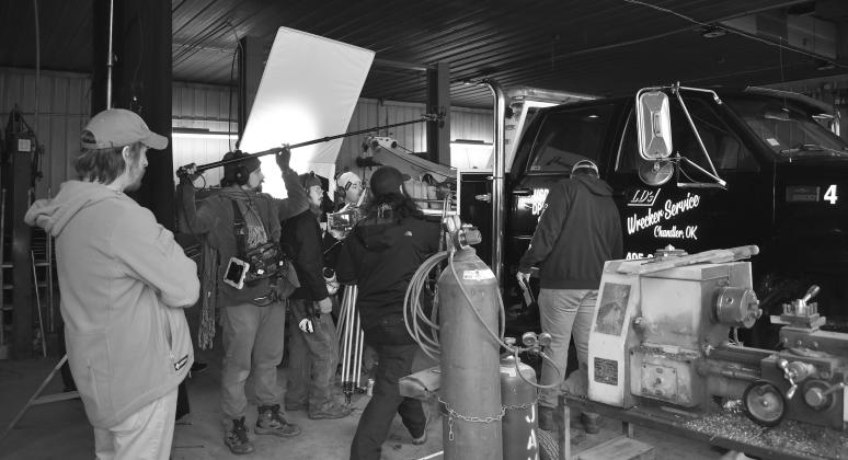 Director Kyle Kauwika Harris (center) gives input on the set of “Reverence” as they film a scene at LD’s Wrecker Service in Chandler while producer Jacob Snovel (far left) watches on. The mystery thriller movie will be filming in town until the end of December. Photo/Emily Kalka