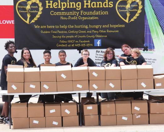 (left to right) Thomas Denson, Helping Hands Community Foundation director Sabra Denson, Jordan Denson, Jaydan Denson, Jeramiah Taylor, Robin Hatfield, Cassondra Wright-Taylor and Iridessa Wright-Taylor set up 100 food boxes to give out at a drive-thru style event Saturday, June 27. Photo/ Kendra Johnson
