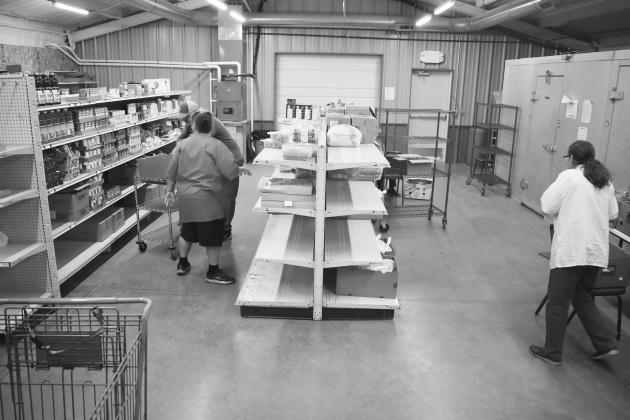 Volunteers from the First Christian Church in Chandler stock the shelves at God and Peoples Pantry on Saturday morning before opening the doors. The Pantry served about 55 families that day. The Methodist Church was also there, cooking hot dogs. They provide hot meals on the last Saturday of every month. Photo/Emily Kalka