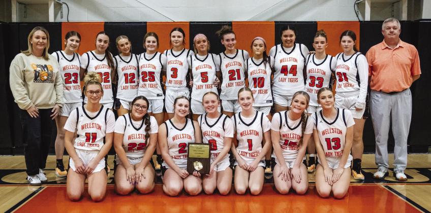 Wellston’s Lady Tigers pose Saturday night with the championship plaque from the Davenport Hardwood Classic. The WLTs beat Meeker, 27-21, in the championship game to remain unbeaten. Photo/Jeremy Self