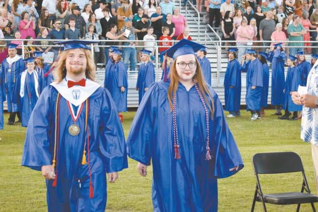 Above, Joel Telford and Elizabeth Myers walk down the aisle to their seats during the graduation ceremony at Joe Telford Field on May 16. Below, Greg Crum from the Class of 1987 waves a flag during the Chandler Alumni Parade on May 17. Photo/ Emily Kalka