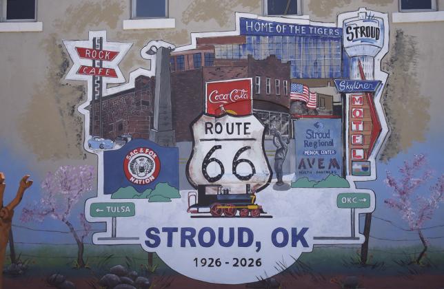 Muralist Bob Palmer sits in front of the Route 66 mural, below, he painted on the side of True Value Hardware store in Stroud.