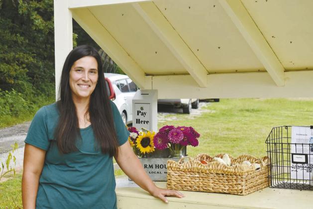 Above, Erica Morris stands in front of her self-service farmstand, Scissortail Meadow Farmstand, where she sells produce and cut flowers. Below, Crystal Earp stands next to Cluck and Crumble, her farmstand where she sells baked goods and eggs. Bottom, a basket of different produce is laid out at Scissortail Meadow Farmstand. Photos/Emily Kalka