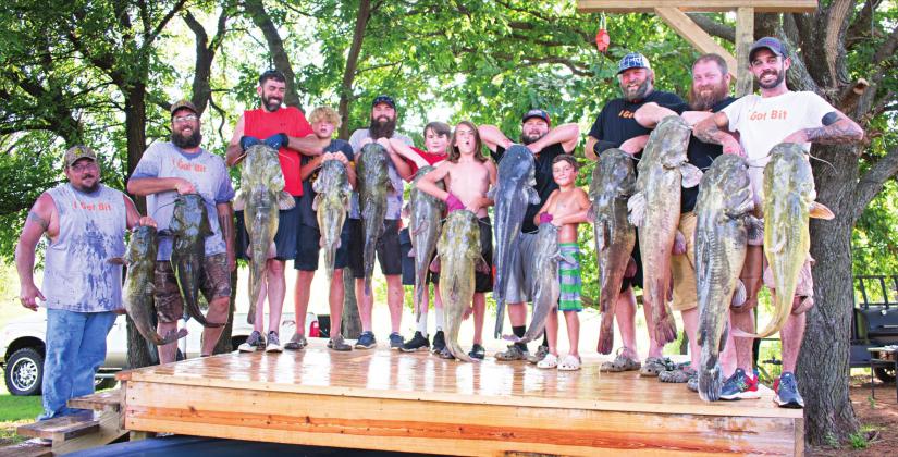 Top, all four competing teams in the Noodling tournament stood with the large fish they noodled out of the water.