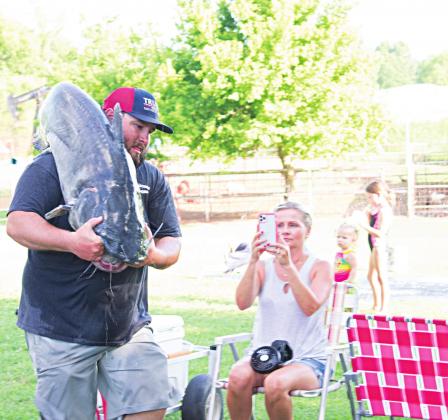 Left, Jered Monroe carries his catfish from the livewells in the back of a pickup truck to the tournament well where they would wait to be weighed. Photos/Chelsea Weeks
