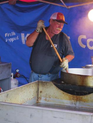Pictured to the top right, Rick Smith with Dad’s Old Fashioned Kettle Corn and Prok Skins slowly stirs the pot as he makes his kettle corm.