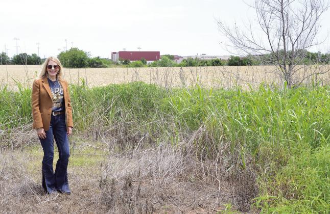 Pottwatomie County District 1 Commissioner Melissa Dennis stands on the edge of state Highway 18 where a new road will connect the highway to North Rock Creek High School, shown in the background. Photo/Brian Blansett