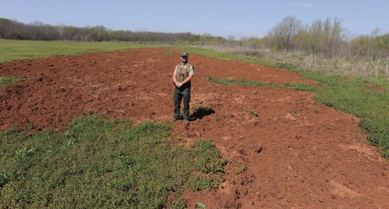 State Game Warden Jacob Harriet, who is assigned to Lincoln County, stands in a field where wild hogs have uprooted a portion of a crop in the Sparks area. Harriet and State Game Warden Mike France, assigned to Pottawatomie County, indicate numbers of wild hogs are increasing across both counties. Photo/Brian Blansett