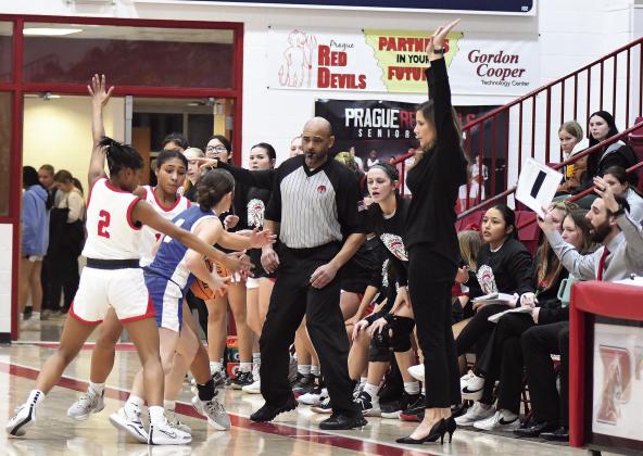 McLoud girls coach demonstrates the straight-up defense she wants from Liese Johnson (2) and Chloe Mapira during a doubleteam late in the Lady Redskins’ come-frombehind win over Holdenville in the semifinals. Photo/Brian Blansett