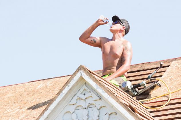 Josef Mackiewicz takes a water break sitting on the roof of a residential work site between Davenport and Chandler. More photos on Page 7A. Photo/Kendra Johnson.