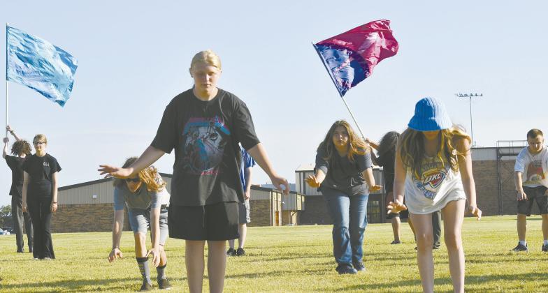Damon Brown (center), along with Suzeanna Asher, Brooklynn Davis and Ayden Isaak to the right and Alexander St. Clair and Keelie Vaughn to the left, work through the formation for their marching band program for this year on July 24 at McLoud High School. Photo/Emily Kalka