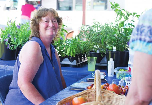Pictured above, Lisa Patton sits encompassed by her tomato and basil plants. Pictured to the right, Victoria Groves has been baking for years, but this is the first season she sells her goods at the farmers market. Pictured to the lower left, Micheal and Ashley McCorckle of Perkins are surrounded by the Paparazzi jewelry and home made home decor. Pictured to the lower right, cousins Sherissa Banman and Makenzie Plett stand next to their homemade jams and blackberries that they picked. Photos/Chelsea Weeks