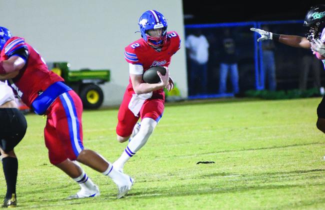 Above, freshman Sam Hall (42) watches the ball into his hands for a two-point conversion catch as fans in the end zone look on. Below, quarterback Alec Jackson cuts through a hole. Photos/Brian Blansett