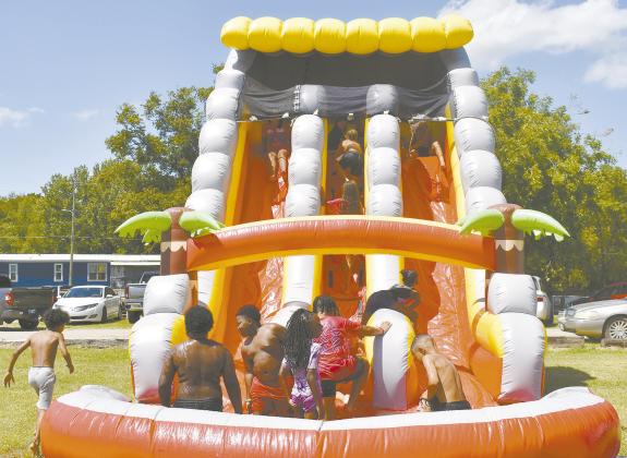 The community of Chandler gathered at the fairgrounds on Aug. 16 for the annual Unity in the Community event, hosted by the Pastor’s Roundtable. The event had live music, inflatables, food and booths by local churches and government agencies. Above, a group of youth performs a spoken word program on unity and justice. Left, children take turns going down the large water slide. Photos/Emily Kalka