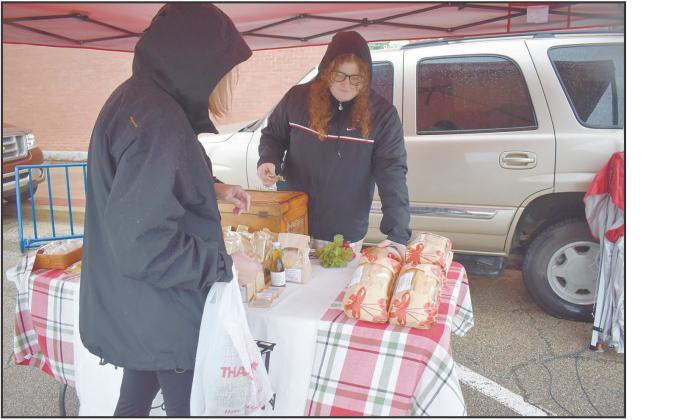 Paige Coyle (right) from Coyle Family Farms helps a customer pick out a loaf of sourdough bread at her stall on April 5. It was the opening day of the season for the 2A Chandler OK Farmers Market. Photo/Emily Kalka