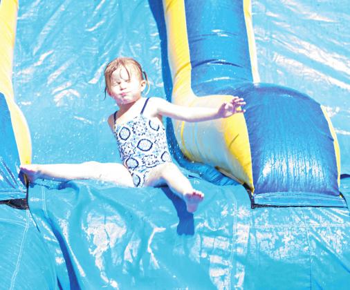 Hannah Donovan, above, slides down the waterslide bouncy house in the Kids Zone at the Deep Fork River Festival in Wellston Saturday, July 18. Photo/Chelsea Weeks