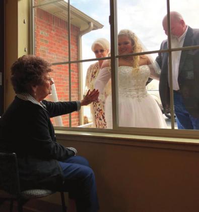Prairie Pointe resident Martha Bookout, pictured to the left, greets her granddaughter Liz Bookout through the glass before her wedding Saturday. Due to COVID-19, many family members could not attend, but it was important for Liz to see her Nanny on her wedding day. Photo/submitted