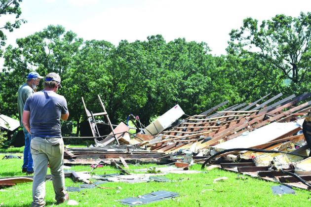 Two men observe the roof of the mess hall at the historic Chandler baseball camp. The building was destroyed last Friday night during severe storms that hit the area. Photo/ Emily Kalka