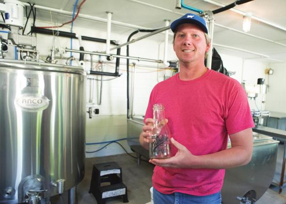 Travis Marak holds one of the milk bottles in the dairy in Meeker. Photo/Brian Blansett