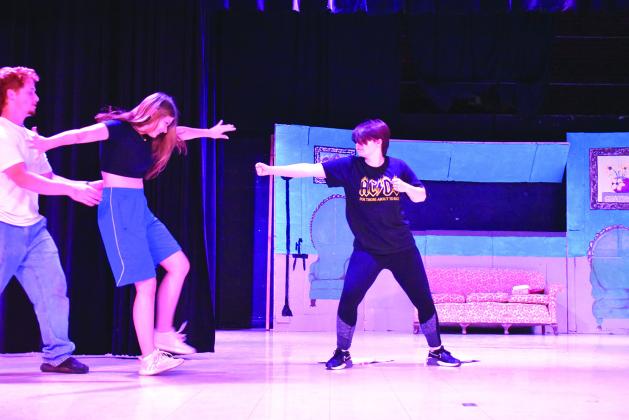 Jordyn Foster-Charkowski, who plays Kinley, throws a punch at Mallory Devers, who plays Mindy, during rehearsal for “A Warrior’s Choice.” On the far left is Joseph Duvall, who plays Dane. The original music marries martial arts and “Mean Girls.” Photo/Emily Kalka