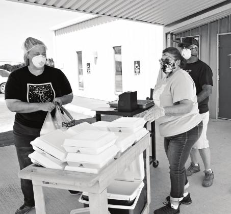 Eboney Schomaker, left, Marilyn Shade and Ike Shade get barbecue lunches ready to hand out at the Project H.E.A.R.T. drive-through in Meeker on Tuesday. Photo/Brian Blansett