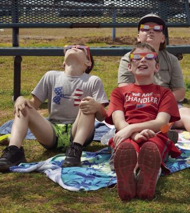 Right, students at Park Road Elementary in Chandler enjoy the warm afternoon at the eclipse viewing held at the school Monday. All the students sat on the playground with special glasses to view the event. From left to right are Bradley Shoopman and Jaxon Carter, with Beau Rogers in the back. Photo/Emily Kalka. Above is a view of the eclipse at totality taken in Antlers. Photo/Aaliyah Coffman