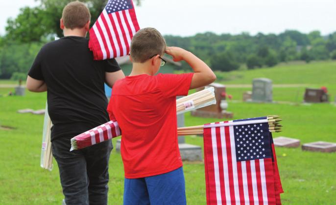 Mason Eversole pauses to salute a veteran’s grave while placing flags at Stroud Cemetery last year in anticipation of the Veterans Day holiday. He is the son of Jerrod and Kristen Eversole. Photo/Lily Huff