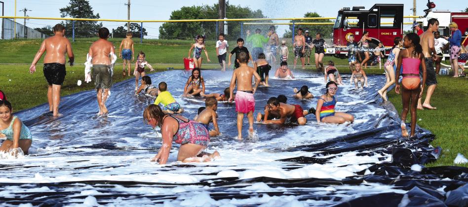 Kids take turns going down the slip and slide put up by the Stroud Fire Department on Saturday during their Fourth of July celebration in Foster Park. Photo/Emily Kalka