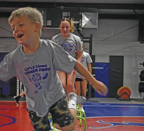 Local kids got active at the Little Lion Summer Pride camp at the Chandler school complex recently They enjoyed a number of workouts and games that got the blood pumping and good times rolling. Above is a group shot of participants in the Freeman Fieldhouse and to the right is a photo of kids jumping over hurdles in the Chandler wrestling room. Photos/Emily Kalka