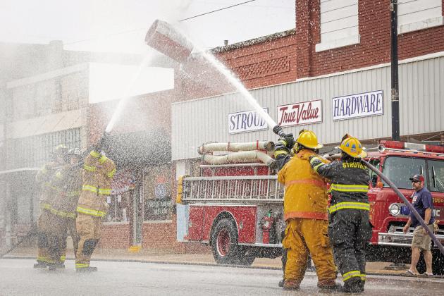 Firefighters in full gear compete Saturday at the annual Stroud Fest Firetruck Muster and Car Show. In this event, teams try to move a suspended barrel to other team’s end. For more on the event and Chandler’s Ice Cream Festival, please see Page 2A. Photo/Evan Kennemer.