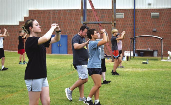Above left, the brass section moves through a scale during Chandler’s marching band camp on July 31. On the right, Mr. Fisher helps a student correct during marching drills. Photos/Emily Kalka