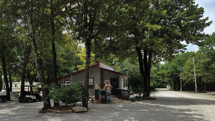Two residents stand in front of the main office at Oaklake Trails Naturist Resort, located between Depew and Stroud. The resort opened in 1992 and has expanded and added to its facilities over the past 32 years. Set on over 400 acres, the park has over 12 miles of hiking trails, 117 lots, 14 cabins, and tent camping spots. Photo/Nate McPherson