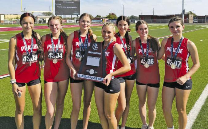 Prague’s girls cross country team, above, brought home state runnerup hardware from the Class 3A meet Saturday at Carl Albert High School. From left are Jae Evig, Jaxi Friend, Hailey Johnson, Jocelyn Ward, Brynlee Smith, Lakeyn Kinslow, and Hanna Rolette. Photo/Monica Johnson. At left is Ward as she motors toward a fourth-place finish. Photo/Brian Blansett.