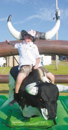 Hughes, who recently moved here from Texas, tries his hand at riding the mechanical bull at the annual Independence Day celebration sponsored by the Meeker Chamber of Commerce. Photo/Brian Blansett