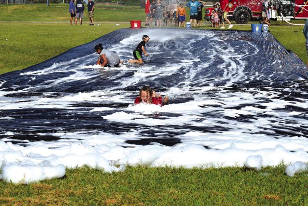 Alittle girl glides her way down the slip and slide at Foster Park in Stroud on Saturday, during the town’s Fourth of July event, before the storms moved in. Photo/Emily Kalka