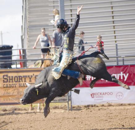 Above, Amelia Knowles from New Zealand, Molly Harper, Ruby Ruckwood, Cade Ferguson and Hope Doyle from Australia, smile for their team photo. Below, Cade Ferguson holds onto the bull rope as the bull attempts to buck him off. Photos/Jentezen Smith