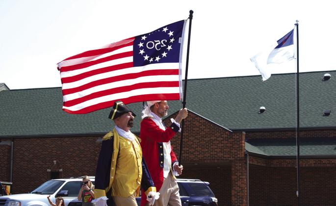 Two members of the Class of 1976 proudly carry a semiquincentennial flag down Manvel Avenue ahead of the class’ float. The class chose to represent the United States’ birthday and iconic spots on Route 66 in Chandler for its three-part float in the parade. Photo/Emily Kalka