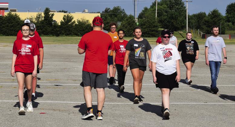Above, Zoe Randall mimes holding an instrument as she and other members of the Pride of Meeker go over marching at Meeker’s band camp. Photo/Brian Blansett. Below and to the right, Director Tony Thoma inspects a line of students. Thoma said the band is focusing on skill and technique this year. Photo/Brian Blansett. At the bottom, Director Trevor Harrold walks the Pride of Prague through marching basics on Monday morning, the first day of their week-long band camp. Photo/Emily Kalka