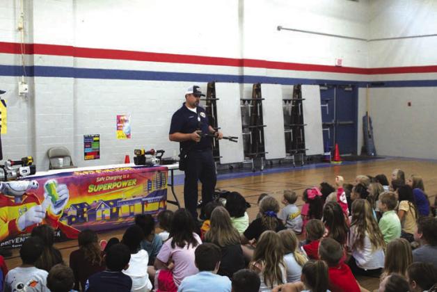 The Chandler Fire Department spent time at East Side Elementary teaching kids about fire safety last week. In the photo on left, Ben Froh shows off his gear to a curious child. On the right, Asst. Fire Chief Tony Rednour explaining what a halligan bar is and how it works. Photos/Landon Gray
