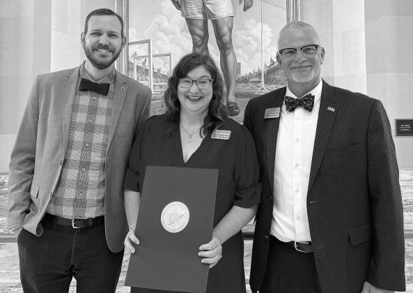 North Rock Creek Principals Chad Brooking (left) and Justin MacDonald (right) smile with Charity Hobbs at the Oklahoma Capitol building after presenting her award.