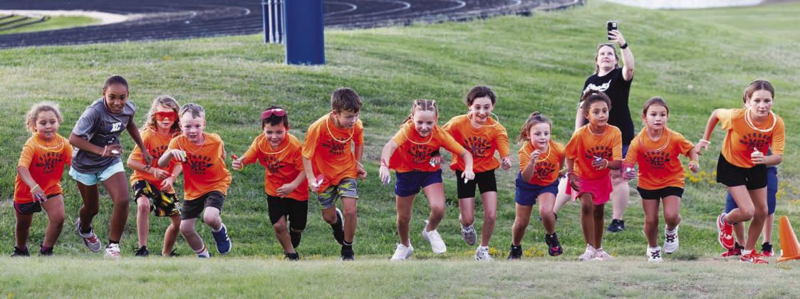 Stroud’s elementary cross country team had its annual end-of-the-season glow run last week. The runners get glow sticks and glow items to wear, run a short 1-mile course around campus and finish with ice cream sundaes. Below is Cayenne Martin. Right, coach Kelly Brown poses with a unicorn (Laney Manion) and shark (Sophie Young), both of whom accompanied the runners on the course. Photos/Beth Young