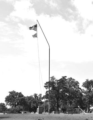 The flag pole in Oak Park Cemetary is bent by strong winds during Friday night’s storm. Photo/Emily Kalka