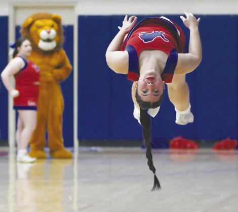 Chandler cheerleader Macie Davis catches a lot of air while doing a series of flips Saturday night during Chandler’s district tournament game against the Morris boys. Watching are cheerleader Calista Schardt and Leo the Lion. Photo/Brian Blansett