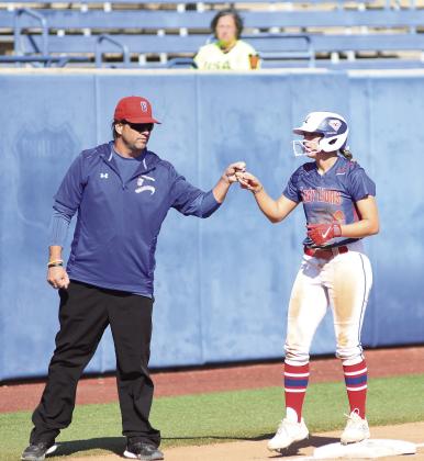 Chandler senior Jaylee Ventris gets a fist bump from coach Bryan Herring after reaching third base during Chandler’s win over Lindsay in the state tournament. Photo/Brian Blansett